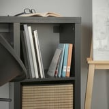 Moderní černá knihovna s přehledně uspořádanými knihami a košíky z přírodních materiálů.