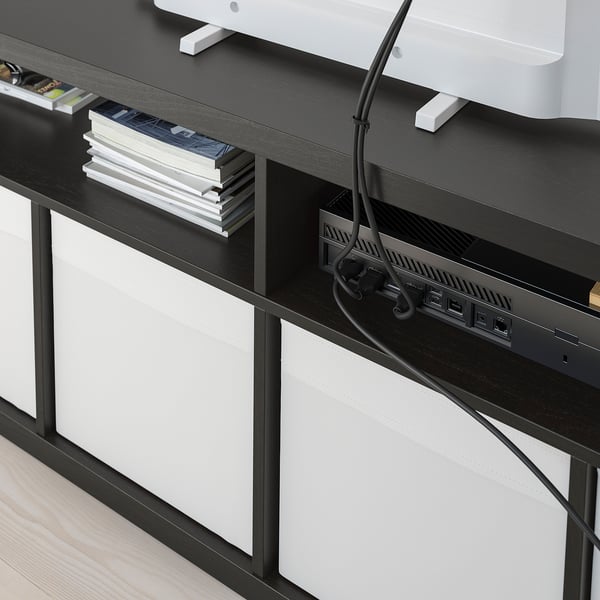 Černý televizní stolek KALLAX s bílými zásuvkami, zobrazující uspořádané kabely a usb rozbočovač, navržený pro snadné vedení kabelů.