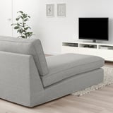 Moderní obývací pokoj s šedou látkovou lenoškou KIVIK, TV na stojanu, rostlinou, minimalistickým dekorem.
