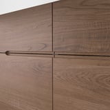 Elegantní příborník z dubové dýhy s hladkými úchytkami, který se vyznačuje špičkovým řemeslným zpracováním a přírodní strukturou dřeva.