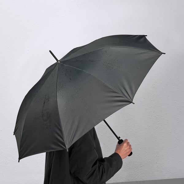 Osoba držící černý deštník KNALLA, který se automaticky otevírá jednou rukou.