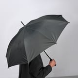 Osoba držící černý deštník KNALLA, který se automaticky otevírá jednou rukou.