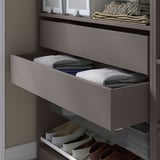 Zásuvka KOMPLEMENT v šedé barvě se skládaným oblečením, součást šatního systému, organizovaný a minimalistický design.