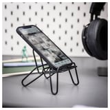 Stojánek na telefon s názvem KRUBBET, vyrobený z oceli s černým práškovým nástřikem, pojme smartphone. Jedná se o jedinečný design podobný stativu.