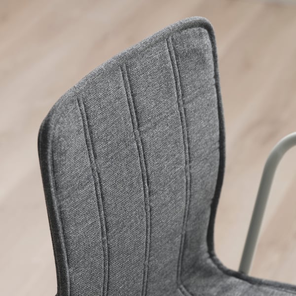 Detailní záběr na moderní, elegantní židli s šedou texturovanou látkou, která předvádí kvalitní prošívání a design.