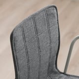 Detailní záběr na moderní, elegantní židli s šedou texturovanou látkou, která předvádí kvalitní prošívání a design.