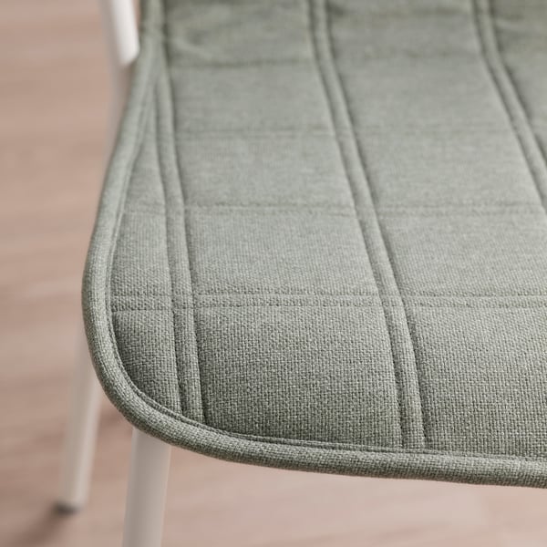 Detailní záběr plyšového, texturovaného polštáře židle na moderním sedadle, který představuje vysoce kvalitní materiály a hladké prošívání.