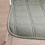 Detailní záběr plyšového, texturovaného polštáře židle na moderním sedadle, který představuje vysoce kvalitní materiály a hladké prošívání.