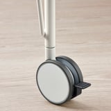 Detailní záběr kola kancelářské židle s hladkým, reflexním povrchem a robustním kovovým dříkem. Vyzdvihuje robustní design a kvalitní konstrukci.