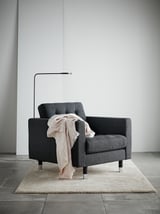 Útulné dřevěné uhlí s útulným přehozem na tvářenku; Moderní minimalistický design, podlaha z tmavého tvrdého dřeva, elegantní lampa.