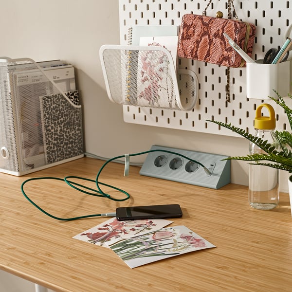 Organizovaný pracovní prostor: stůl s nabíjecím telefonem, zařízení a úložný prostor.