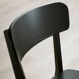 Černá dřevěná židle s hladkým povrchem, zakřiveným opěradlem a robustními nohami. Elegantní a moderní design.