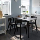 Malý moderní černý jídelní set s elegantním obdélníkovým stolem a polstrovanými židlemi, který se dokonale hodí do kompaktního kuchyňského prostoru.