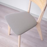 Moderní dřevěná židle se zakřiveným opěradlem, s plyšovým látkovým sedákem, posazená na světlé dřevěné podlaze.
