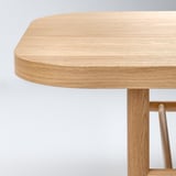 Detailní záběr na elegantní desku stolu z přírodního dřeva. Hladké, světlé dřevo s jemnou kresbou a robustní konstrukcí.