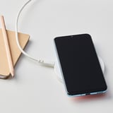 Nabíjecí podložka LIVBOJ s modrým telefonem, USB-C kabelem, notebookem a tužkou. Bezdrátové, přenosné, moderní pracoviště.