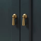 Tmavě modrá skříňka se dvěma elegantními, leštěnými zlatými úchyty, které představují stylový a funkční hardware.