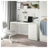 Moderní bílé uspořádání stolu s bílou židlí, notebookem a úložnými jednotkami. Čistý a minimalistický design s otevřenými policemi a dírkovanou deskou.