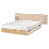 Světlá dřevěná postel s názvem MANDAL. Má lamelové bočnice a jednoduchý, minimalistický design.