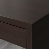 Moderní psací stůl z tmavého dřeva s elegantními hranami a otvorem pro vedení kabelů na zadní straně, který ukazuje kvalitní řemeslné zpracování.