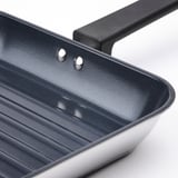 Detailní záběr moderních grilovacích pánví, nepřilnavého povrchu a robustní rukojeti. Elegantní a odolný design.