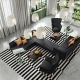 Moderní lobby s černou pohovkou, křesly a výškově nastavitelnými stolky na notebook.