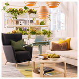 Moderní obývací prostor s šedou židlí, bílou pohovkou, stolem na notebook a barevnou výzdobou.