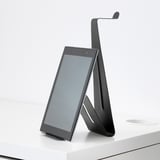 Moderní stojan na tablet v černé barvě držící tablet ve vzpřímené poloze na bílém stole.