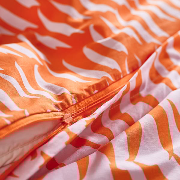 Detail barevného povlečení s tygřími pruhy a viditelným oranžovým zipem.