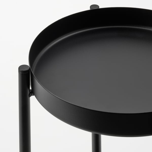 Kulatý černý podnos na nožičkách. Moderní design, hladký povrch.