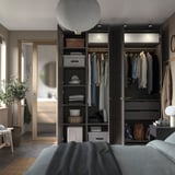 Moderní ložnice se šatní skříní PAX, závěsnou lampou a rostlinou.