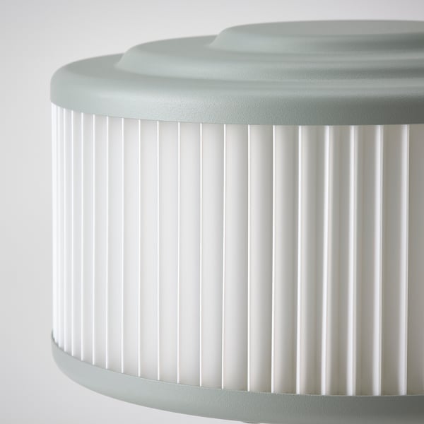 Moderní lampa se skládaným bílým stínidlem, hladkým šedým vrchem a základnou, představující kvalitní design.