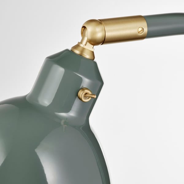 Detailní záběr na moderní lampu s elegantním zeleným stínidlem a zlatými akcenty, která ukazuje její kvalitní design a materiály.