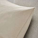 Detail béžového polštáře na čalouněné židli, který představuje měkký bavlněný samet se vzorem.