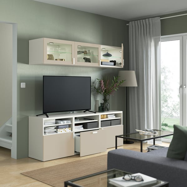 Moderní obývací pokoj s TV na jednotce SINDVIK, prosklenými dveřmi s výzdobou a elegantní lampou vedle okna.