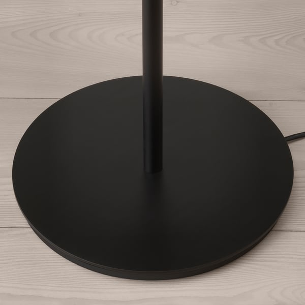 Moderní černý podstavec stojací lampy na podlaze ze světlého dřeva, elegantní design, kvalitní materiály.