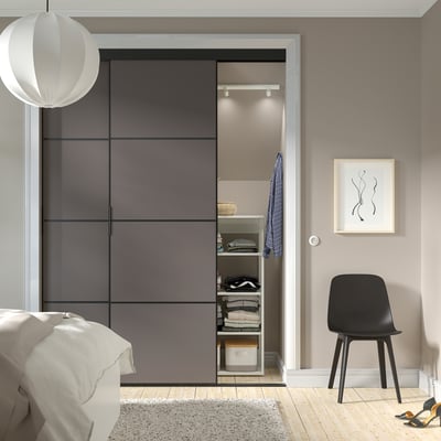 Moderní ložnice s posuvnými dveřmi SKYTTA, černá židle, minimalistický dekor.