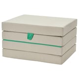 Béžová skládací podlahová matrace SLÄKT se zeleným lemováním ve složeném svazku. Je obdélníkový a určený pro děti.