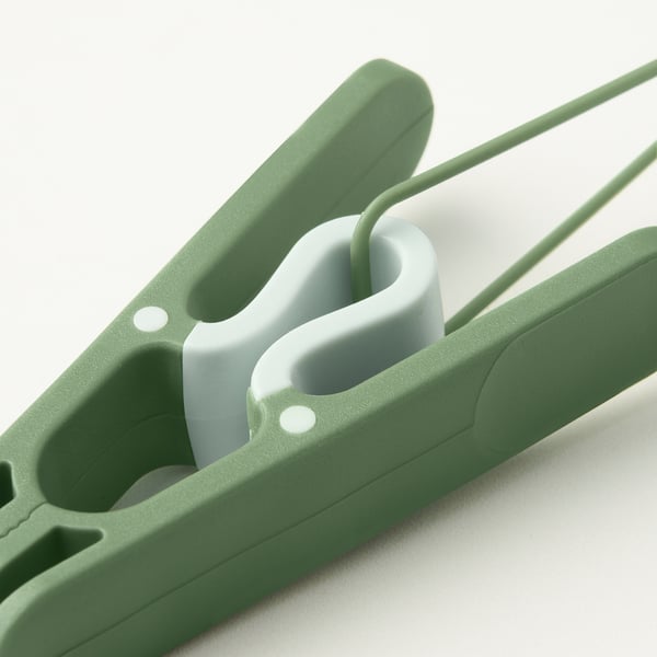 Detailní záběr odolných zelených plastových kolíčků na prádlo s bílým poutkem a robustním upínacím mechanismem.