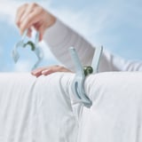 Osoba držící bílé oblečení s velkými modrými odolnými kolíčky na prádlo.