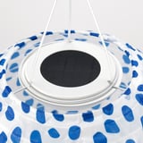 Závěsná lampa s modrým vzorovaným stínidlem. Solární panel a bílá podpěra. Moderní a ekologický design.