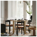 Elegantní jídelní prostředí s moderními skandinávskými židlemi, kulatým stolem, elegantním dekorem.