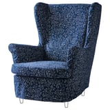 Modré křeslo ušák STRANDMON s květinovým vzorem a černými kovovými nohami. Design je elegantní a pohodlný.