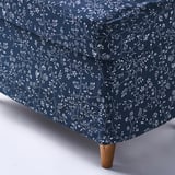 Tmavě modrá podnožka STRANDMON s potahem s květinovým vzorem a dřevěnými nohami, která demonstruje svou vysoce kvalitní látku a klasický design.