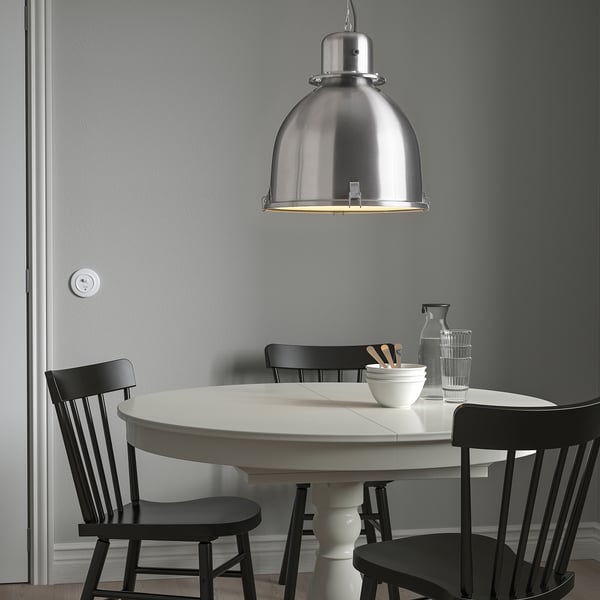 Lampa SVARTNORA, elegantní klenuté závěsné svítidlo nad jídelním stolem s černými židlemi, velké stříbrné ohniskové světlo.