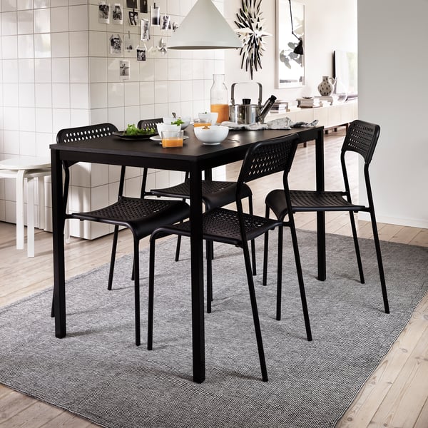 Moderní kuchyňská linka s černou jídelní soupravou, jídlo, bílý backsplash, šedý koberec.
