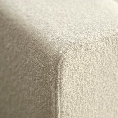 Detailní záběr na měkké, texturované béžové čalounění ukazuje jemné detaily šití, zvýrazňuje kvalitu a řemeslnou zručnost.
