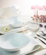 Elegantní prostírání s bílými čtvercovými porcelánovými talíři VÄRDERA, šálky z čirého skla, stříbrnými příbory a ubrousky. Jednoduchý, propracovaný design.