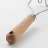 Detail robustního kuchyňského nástroje, zvýraznění dřevěné rukojeti s otvory, moderní a silný design.