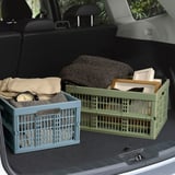 Dvě skládací přepravky VEDKLYV v zelené/modré barvě v kufru auta, na přikrývky a krabice, lehké, plastové s madly.
